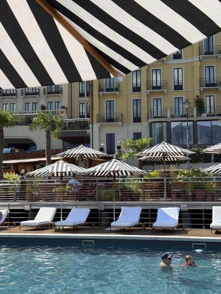 Pool deck at the Lake Como EDITION with striped umbrellas and hotel view