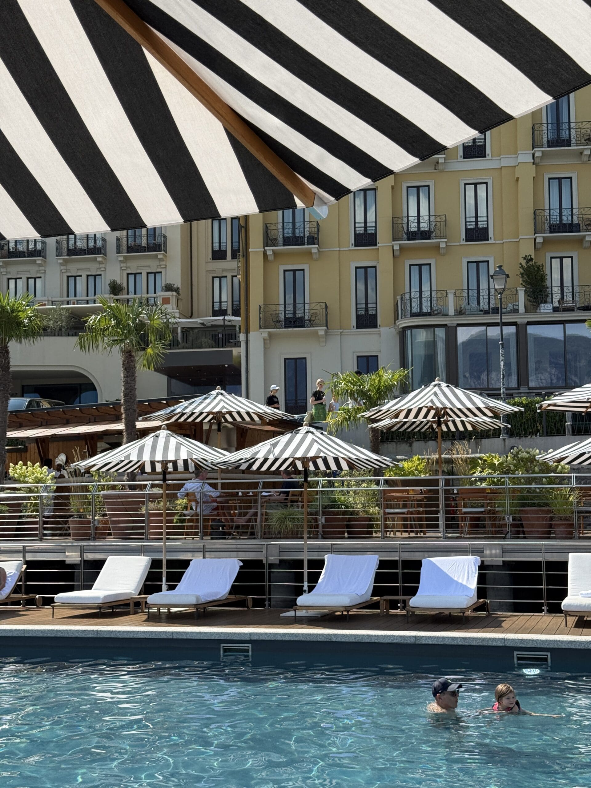 Pool deck at the Lake Como EDITION with striped umbrellas and hotel view